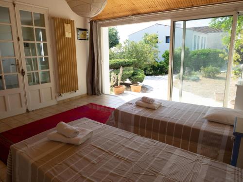 two beds in a room with a large window at Renovated villa by the ocean in Barbâtre