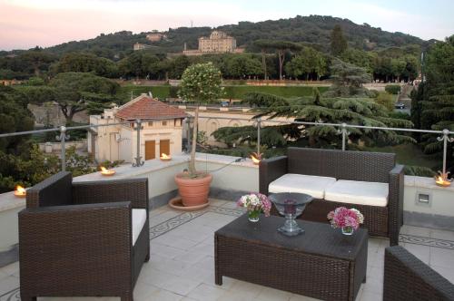 a patio with wicker chairs and a table with flowers at Hotel Flora in Frascati