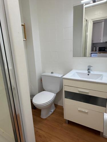 a white bathroom with a toilet and a sink at Apartamento Cala En Bosch B10 in Cala en Bosc