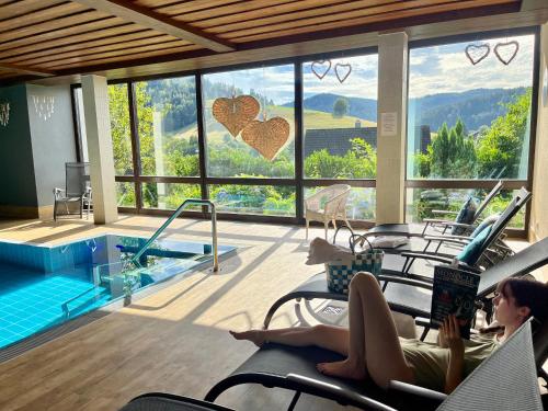 two women sitting in chairs in front of a swimming pool at Goldener Hahn Ferienwohnungen Pool, Sauna & Frühstücksservice in Baiersbronn