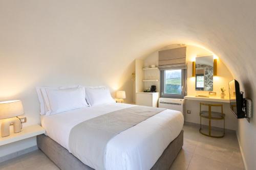 a bedroom with a large white bed and a kitchen at Maiandros Suites in Karterados