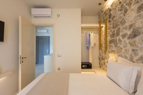 a bedroom with a bed and a stone wall at Maiandros Suites in Karterados