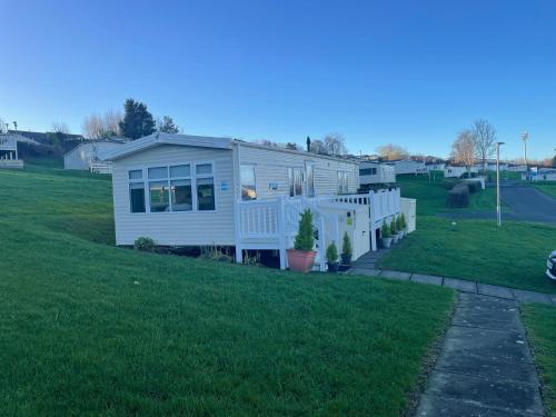 a white house on a green field with a yard at JSNHolidays at Craig Tara Holiday Park in Ayr