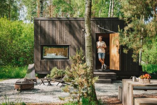 a man is standing in the doorway of a tiny house at Hidden Base - romantyczna leśna kryjówka in Smolarnia