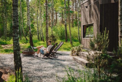 a man sitting in rocking chairs in the woods at Hidden Base - romantyczna leśna kryjówka in Smolarnia
