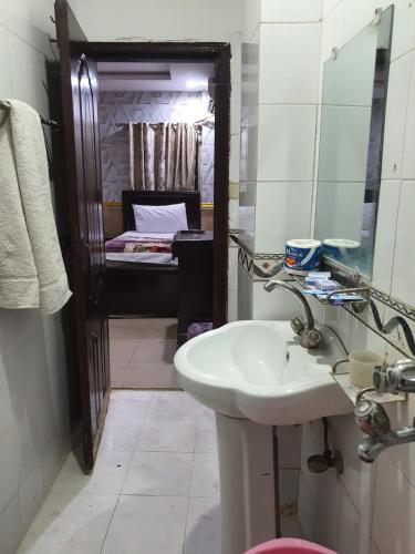 a bathroom with a sink and a mirror and a bed at Hotel The Shalimar in Lahore