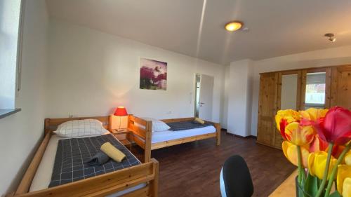a bedroom with two beds and flowers in a room at Bright Rooms with WiFi , Terrace between Freiburg and France , private Zimmer in Freiburg im Breisgau