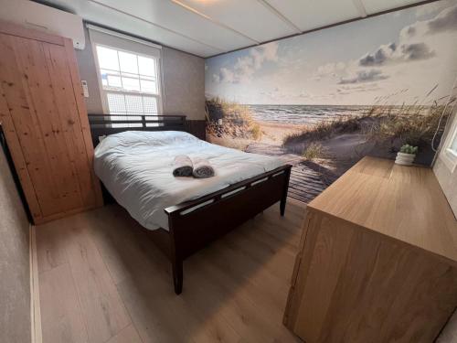 a bedroom with a bed and a painting of a beach at Beach House Giethoorn in Wanneperveen