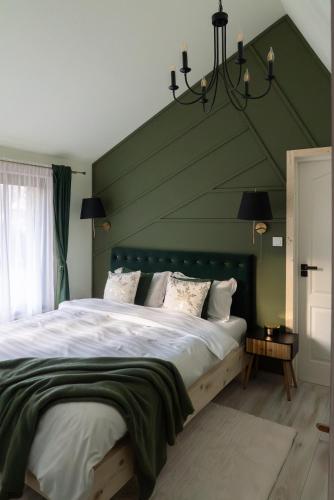 a bedroom with a large bed with a green wall at Acasa Straja - Green Cottage in Lupeni