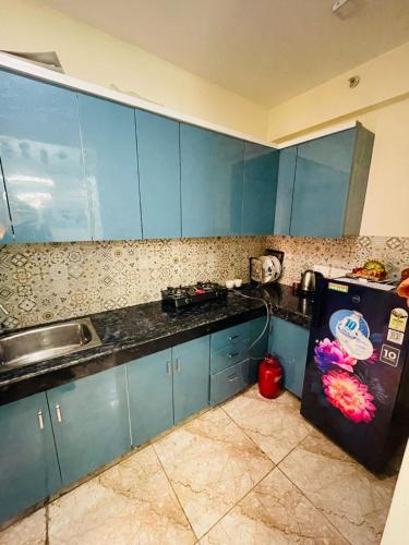 a kitchen with blue cabinets and a refrigerator at AM Living in Ghaziabad