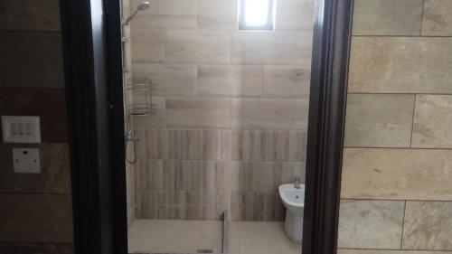 a bathroom with a toilet and a shower with a glass door at منزل ومزرعه للايجار الشوبكً Farm for rent , Shoubak , Petra in Nijil