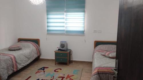 a bedroom with two beds and a tv on a table at منزل ومزرعه للايجار الشوبكً Farm for rent , Shoubak , Petra in Nijil