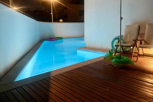a blue swimming pool with a chair and a table at Signature Guesthouse in Porto