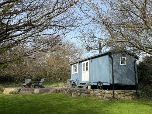 a tiny house sitting on top of a stone wall at Bluebell Shepherd's Hut in Llanfair