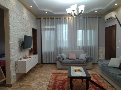 a living room with a couch and a tv at The Garden Guest House in Divjakë