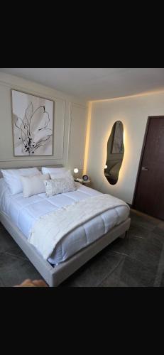 a bedroom with a large white bed with two pictures on the wall at Puntacero Fundidora 1604 Cintermex in Monterrey