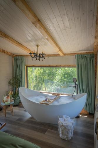 a large white tub in a room with a window at Acasa Straja - Treehouse in Lupeni