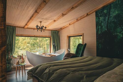a bedroom with a tub and a bed and a window at Acasa Straja - Treehouse in Lupeni