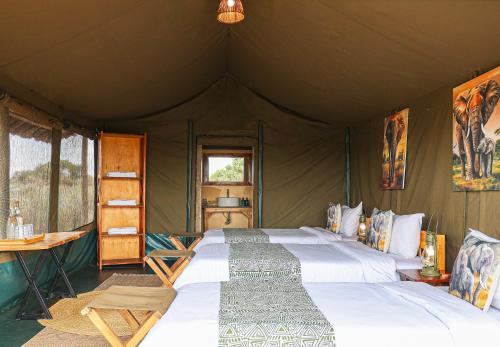a bedroom with two beds in a tent at Amboseli Discovery Camp in Amboseli