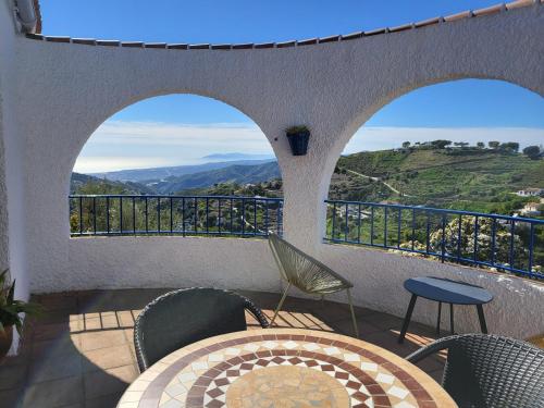 a balcony with a table and chairs and a view at B&B la Madrugada in Cómpeta