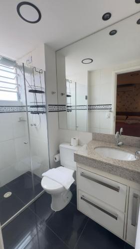 a white bathroom with a toilet and a sink at Apartamento Exec Premium Queen Bed Centro-Taubate in Taubaté