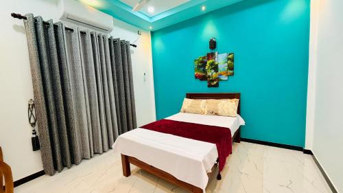 a bedroom with a bed and a blue wall at Asmi Villa in Jaffna