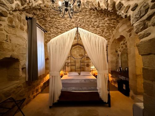 a bedroom with a bed with curtains and a chandelier at Sümerler Konağı in Mardin