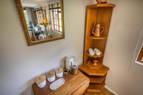 ein Zimmer mit einem Spiegel und einem Holztisch mit Geschirr in der Unterkunft Khanyeni in Himeville