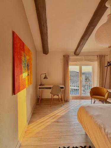a bedroom with a bed and a desk and a window at La petite fontaine in Bédoin