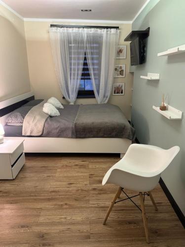 a bedroom with a bed and a chair and a window at Apartament Alan in Kłodzko