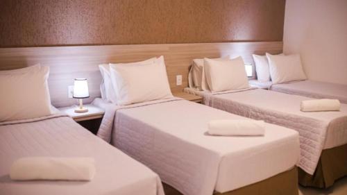 a room with three beds with white sheets and a lamp at China Park Eco Resort in Domingos Martins