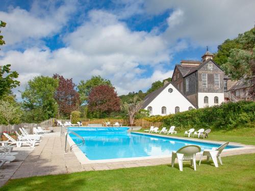 a pool with chairs and a house in the background at Tuckenhay, Edgecombe Barn- Hfu in Ashsprington