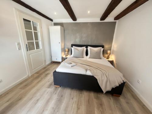 a bedroom with a large bed with white walls and wooden floors at Hof Steinhütten in Westerhever