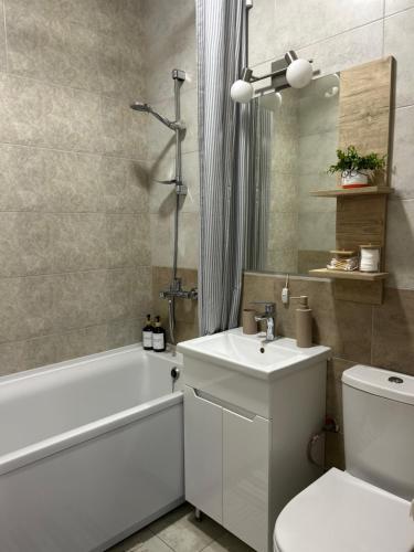 a bathroom with a sink and a tub and a toilet at Sisters apartment Val in Chernihiv