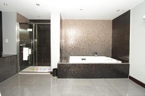 a bathroom with a tub and a glass shower at Rafayel Hotel & Spa in London