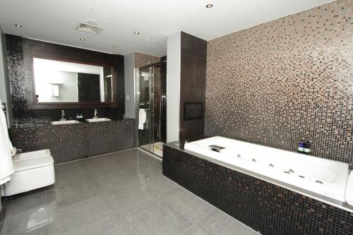 a bathroom with a tub and a toilet and a sink at Rafayel Hotel & Spa in London
