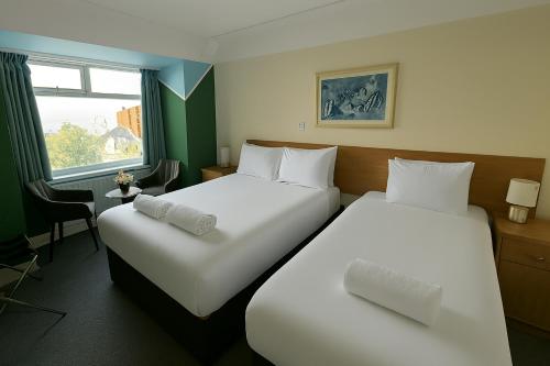 a hotel room with two beds and a window at Russel Court Hotel Bournemouth Central in Bournemouth