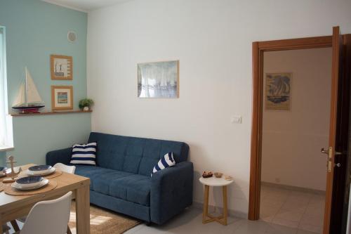 a living room with a blue couch and a table at Velaria Apartment in Termoli