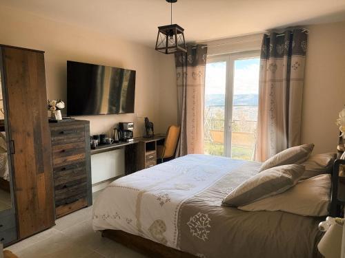 a bedroom with a bed and a tv and a window at Les Crins Du Bonheur Chambre et Table Hôtes Belle Vue in Fraisse