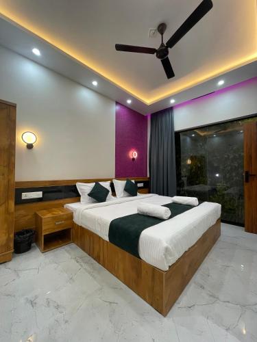 a bedroom with a large bed with a ceiling fan at Neev holiday homes in Vythiri