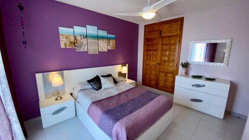 a bedroom with a purple wall with a bed and a door at Paraíso de playas y luz in Alcossebre