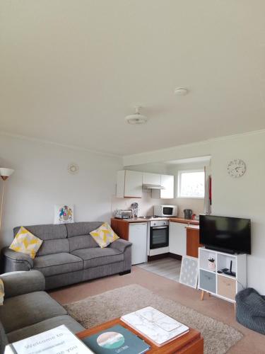a living room with a couch and a kitchen at The Warren Chalet in Cromer