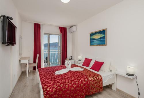 ein Hotelzimmer mit einem Bett mit roter Tagesdecke in der Unterkunft Hotel Azzurro in Herceg-Novi