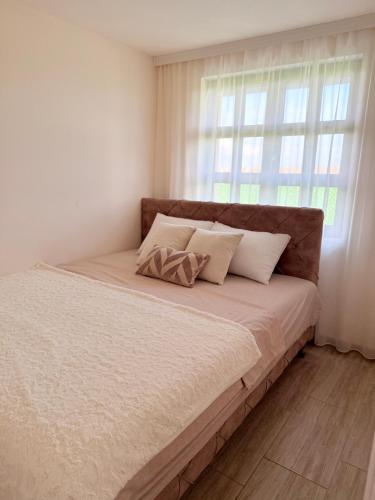 a bed with two pillows and a window in a bedroom at Vikendoria Pool House & Events in Bački Jarak