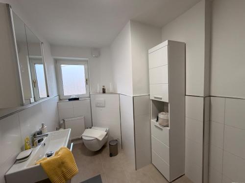 a white bathroom with a sink and a toilet at Miras Guesthouse Ferienwohnung in Lengerich