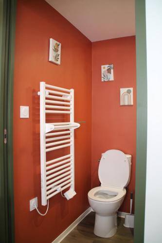a bathroom with a toilet and orange walls at chez laetitia proche du puy in La Flocellière