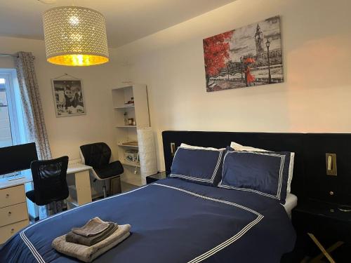 a bedroom with a bed with blue sheets and a desk at Host-Free Ensuite Double Bed by Heathrow in Feltham