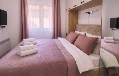 a bedroom with a large bed with two white towels at Alma Apartment - Family Stay Across Aqua Park Raj in Vrnjačka Banja