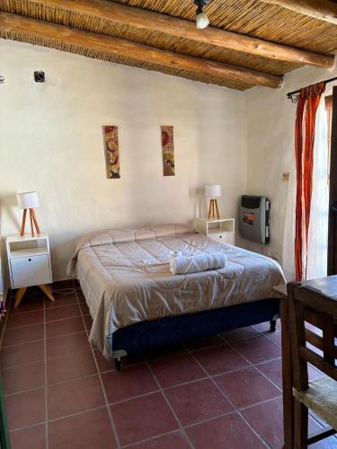a bedroom with a bed and two tables and two lamps at Giramundo Hostel Purmamarca in Purmamarca