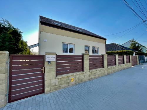 a house with a brown fence and a building at Aurum Vendégház in Esztergom